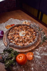 Pizza on wooden background with tomatoes, mushrooms,  basil and mozzarella cheese, close up top view