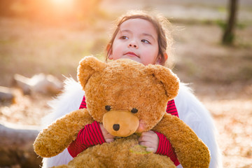 Cute Young Mixed Race Baby Girl Hugging Teddy Bear Outdoors