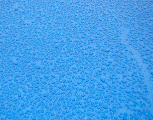 Wallpaper. water drops on metallic blue surface. The apparent grain of the metallic paint appears as grain.
