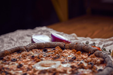 Pizza on wooden background with tomatoes, mushrooms,  basil and mozzarella cheese, close up top view