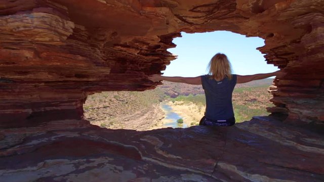 Australian outback in WA. Caucasian woman inside the rock arch sandstone of Nature's Window, looking the Murchison River in Kalbarri National Park, Western Australia.