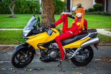 Young attractive girl in red posing with big motorcycle
