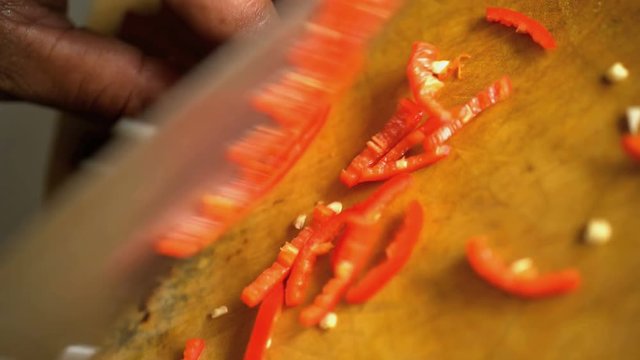 Preparation by hand of salsa using nutritious raw vegetables and chopping with knife on wooden cutting board 