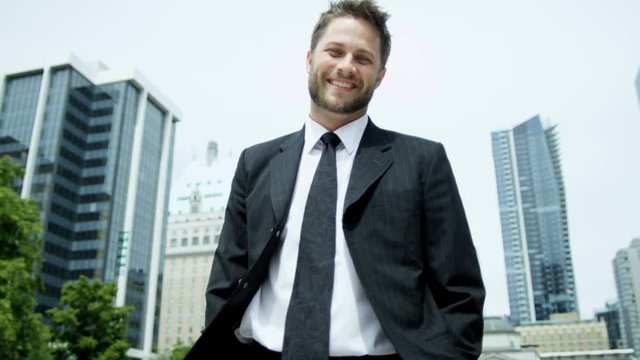 Portrait of ambitious Caucasian American businessman in smart city suit outdoors amongst modern urban skyscrapers 