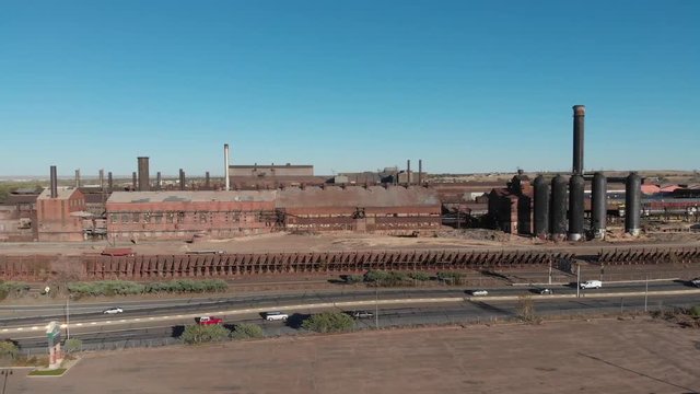 descending full aerial view of rusty old steel mill and smokestacks in industrial setting