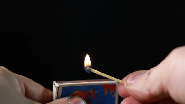 Lighting A Match From Matchbox On Black Background. Macro Close-Up