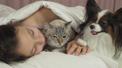 Beautiful teen girl sleeping sweetly in bed with dog and cat