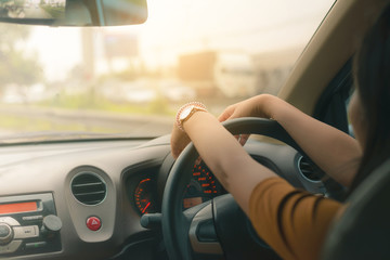  Woman looking bored in her own car while getting stuck in traffic jam.