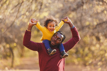 Portrait of happy african dad little boy smiling in the garden.