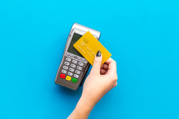 Pay by payment terminal. Paypass  technology. Woman's hand hold credit card, bring card to terminal  on blue background top view copy space - obrazy, fototapety, plakaty