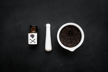Prepare poison. Bottle with skull and crossbones near mortar and pounder on black background top view space for text