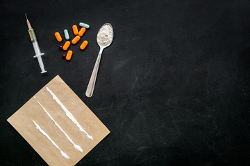 Take drugs, drugs addiction concept. White powder like heroine or cocaine, drug tracks pills, spoon, syringe on black background top view copy space