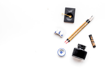 Accessories for chinese or japanese calligraphy. Special writting pen, ink on white background top view copy space