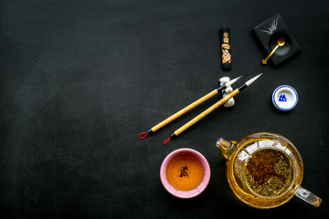 Chinese or japanese traditions. Calligraphy and tea ceremony concept. Special writting pen, ink near teapot and cup of tea, insense on black background top view space for text