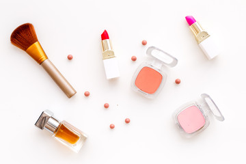 Set of pink cosmetics. Lipstick, bulk, eyeshadow, perfume near brushes on white background top view