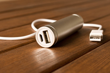 Silver powerbank with connector on wooden table.