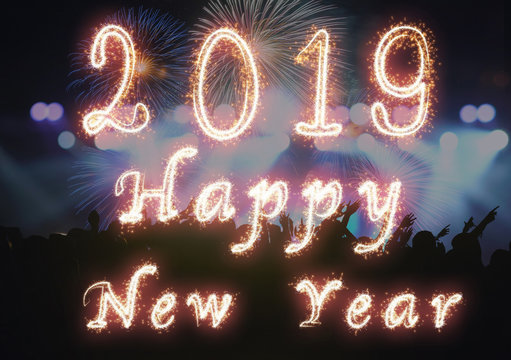 Happy new year 2019 written with Sparkle firework on Concert crowd in silhouettes of Music fanclub with show hand action for celebrate with fireworks, Xmas celebration concept