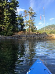 Kayaking towards shore on a beautiful summer evening in Howe Sound, British Columbia, Canada.
