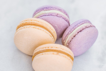 Yellow and purple pastel colored French macarons on white marble table 