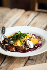 Beet salad with ricotta cheese, oranges and arugula. Wooden table, elegant serving. Food styling photography