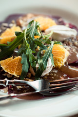 Beet salad with ricotta cheese, oranges and arugula. Wooden table, elegant serving. Food styling photography