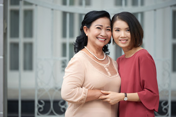 Smiling Asian senior woman and her adult woman smiling at camera