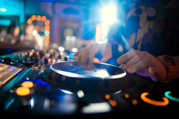 Dj mixes the track in the nightclub at party. In the background laser light show