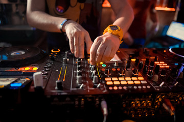 Dj mixes the track in the nightclub at party. In the background laser light show