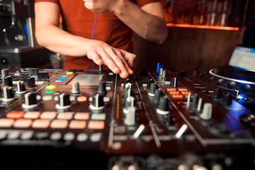 Dj mixes the track in the nightclub at party. In the background laser light show