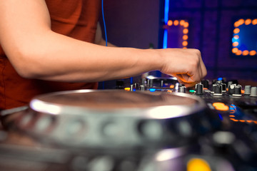 Dj mixes the track in the nightclub at party. In the background laser light show