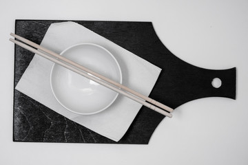 white bowl and napkin, chopsticks on black board