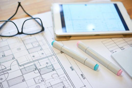 Markers, tablet computer and construction plan on table of architect
