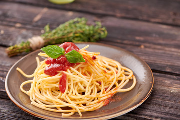 spaghetti with ketchup and Basil on dark wooden background