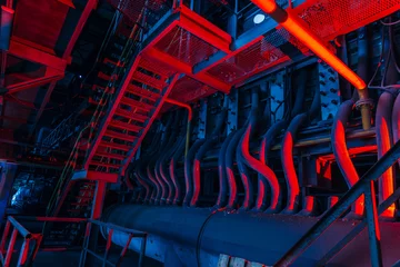 Foto op Plexiglas Binnenkant van oude verlaten fabriek. Roestige geruïneerde industriële pijpleidingverbinding. Abstracte rood verlichte industriële achtergrond © Mulderphoto