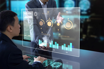 Businessmen in front of future virtual modern computer screen with graphs analysing on investment...