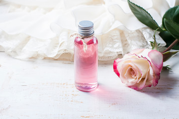 Obraz na płótnie Canvas perfumed rose water in a bottle on a wooden table