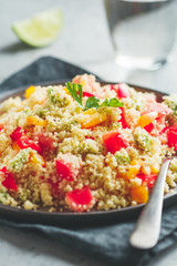 Couscous salad with fresh red and yellow bell peppers, avocado, tomatoes and lime. The concept of vegetarian and healthy food.