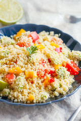 Couscous salad with fresh red and yellow bell peppers, avocado, tomatoes and lime. The concept of vegetarian and healthy food.