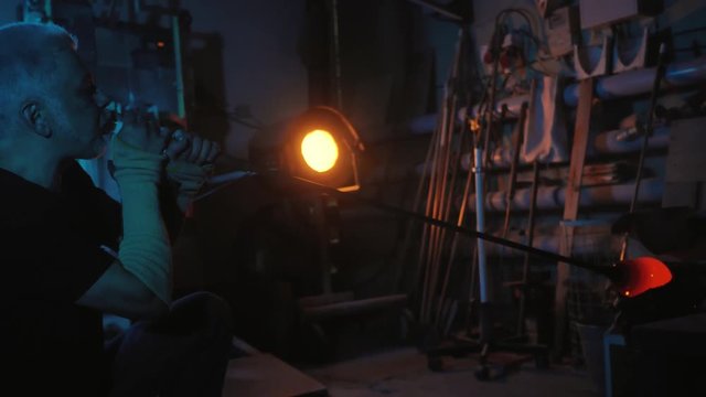 Glassblower free blowing glass at glassblowing factory