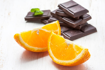 sliced oranges with dark chocolate on a white background wooden