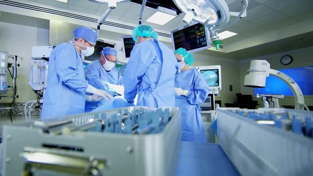 Training surgical medical operating team in scrubs working in indoor hospital theater facility performing Orthopaedic surgery operation on patient with modern equipment 