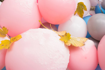 Sad pink inflatable background with fallen autumn yellow leaves under the first snow.