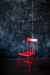 wooden red chair in front of chalkboard