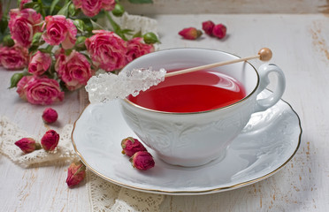 Cup of tea with dried rose buds and fresh roses