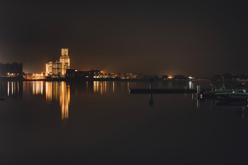 Obraz premium September 3, 2017 - Al Hamra Village in Ras al Khaimah, United Arab Emirates. Night view of water front in Persian gulf with pier, boats and Illuminated arabian luxury hotel reflected in the sea.