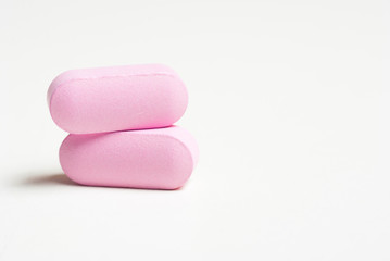 Pink medicine vitamin pills on white