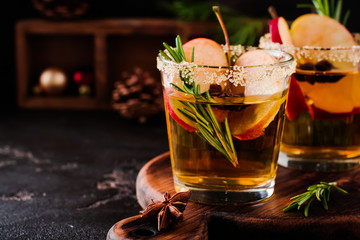 Traditional Christmas apple punch with cinnamon, anise and sprigs of rosemary on dark background...