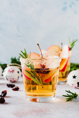 Traditional Christmas apple punch with cinnamon, anise and sprigs of rosemary on light background....