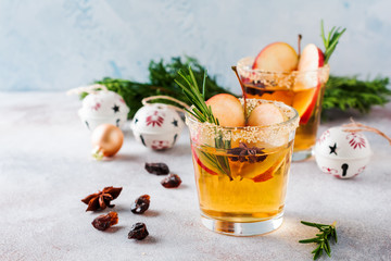 Traditional Christmas apple punch with cinnamon, anise and sprigs of rosemary on light background. Selective fоcus. Top view.