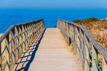 Naklejka premium Wooden path on sand to sea. Vacation and rest on a beach concept